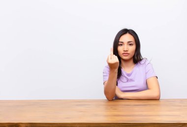 Genç, Latin, güzel bir kadın kızgın, sinirli, isyankar ve agresif hissediyor. Orta parmağını şaklatıyor ve düz duvara karşı savaşıyor.