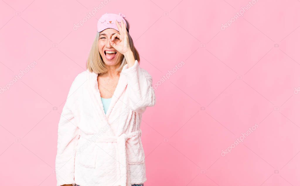 middle age woman smiling happily with funny face, joking and looking through peephole, spying on secrets. night suit concept