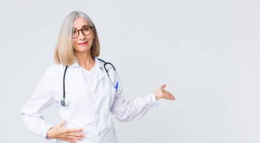 Orta yaşlı doktor kadın kendini mutlu ve neşeli hissediyor, size gülümsüyor ve hoş geldiniz diyor, sizi dostça bir jestle içeri davet ediyor.