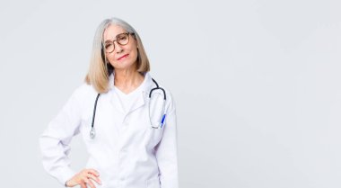 Orta yaşlı doktor kadın gururlu, kendine güvenen, havalı, küstah ve küstah görünüyor, gülümsüyor, başarılı hissediyor.