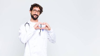 Genç doktor gülümsüyor ve mutlu, sevimli, romantik ve aşık oluyor. İki eliyle fotokopi duvarına karşı kalp yapıyor.