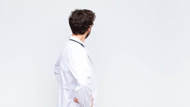 Genç doktor kafasının karışık ya da dolu olduğunu ya da şüphe ve sorular sorduğunu, merak ettiğini, ellerinin kalçasında olduğunu, fotokopi duvarında dikiz aynasının olduğunu.