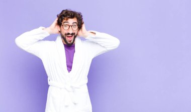 Bornoz giyen genç sakallı adam mutlu, kaygısız, arkadaş canlısı ve rahat görünüyor. Hayattan ve başarıdan keyif alıyor, olumlu bir tavırla.