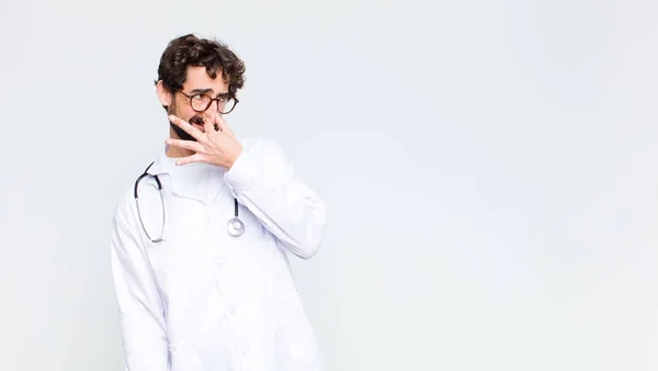 コピースペースの壁に対して汚くて不快な悪臭を避けるために鼻を保持し うんざりしている若い医師の男 — ストック写真