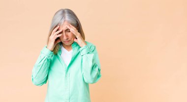 Orta yaşlı, havalı bir kadın stresli ve hayal kırıklığına uğramış görünüyor. Baskı altında çalışıyor, başı ağrıyor ve sorunları var.