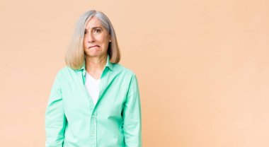 Orta yaşlı, havalı bir kadın hangi seçeneği seçeceğine karar veremiyor, kafası karışık ve kararsız.