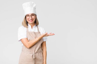 Orta yaşlı fırıncı kadın neşeli bir şekilde gülümsüyor, mutlu hissediyor ve fotokopi odasında bir konsept gösteriyor.