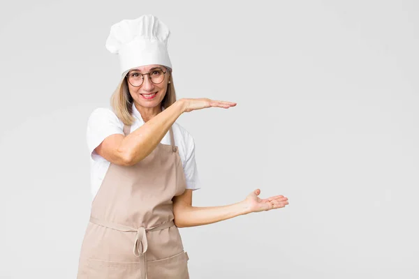 Bäckerfrau Mittleren Alters Hält Einen Gegenstand Mit Beiden Händen Auf — Stockfoto