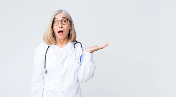 Lekarz Średnim Wieku Kobieta Wygląda Zaskoczony Zszokowany Szczęką Spadła Trzymając — Zdjęcie stockowe
