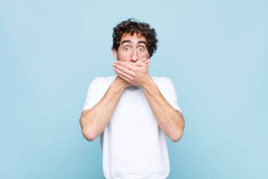 Genç, sakallı, ağzı kapalı, şok olmuş, şaşırmış bir ifadeyle sır saklayan ya da düz duvara karşı 