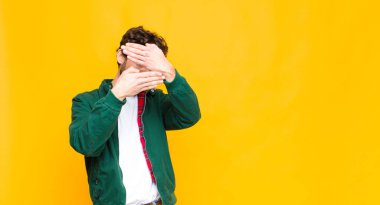 Genç çılgın sakallı adam kameraya hayır diyen iki eliyle yüzünü kapatıyor! Resimleri reddetmek ya da yasaklı fotoğrafları düz duvara yaslamak