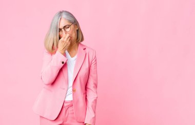 Orta yaşlı havalı kadın iğreniyor, burnundan pis ve tatsız bir kokuyu duvarda hissetmemek için tutuyor.