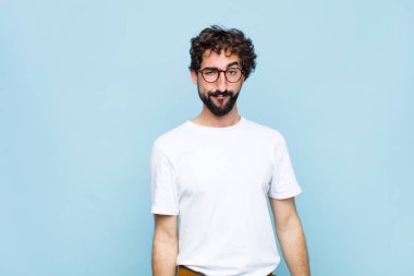 Mavi duvarda gözlüklü genç sakallı adam.