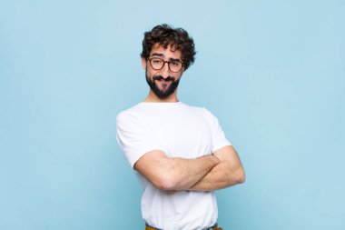 Mavi duvarda gözlüklü genç sakallı adam.