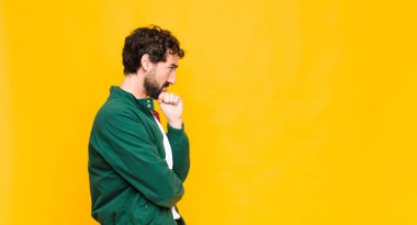 Genç çılgın sakallı adam turuncu duvara karşı kopyalama alanı.