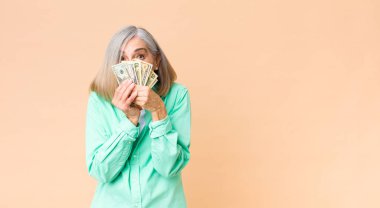 Fotokopi duvarında dolar banknotları olan orta yaşlı güzel bir kadın.