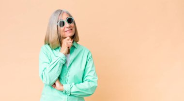 Orta yaşlı güzel kadın fotokopi duvarına güneş gözlüğü takıyor.