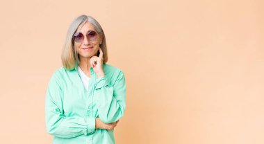 Orta yaşlı güzel kadın fotokopi duvarına güneş gözlüğü takıyor.