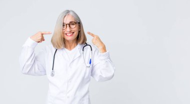 Orta yaşlı doktor kadın kendi gülüşünü gösteriyor, pozitif, rahat, tatmin olmuş tavır.