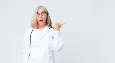 Orta yaşlı doktor kadın inançsızlıktan şaşkın şaşkın bakıyor, yan taraftaki objeyi işaret ediyor ve diyor ki vay be, inanılmaz.