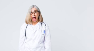 Orta yaşlı doktor kadın korkmuş ve şok olmuş hissediyor, ağzı açık şaşkınlık içinde.