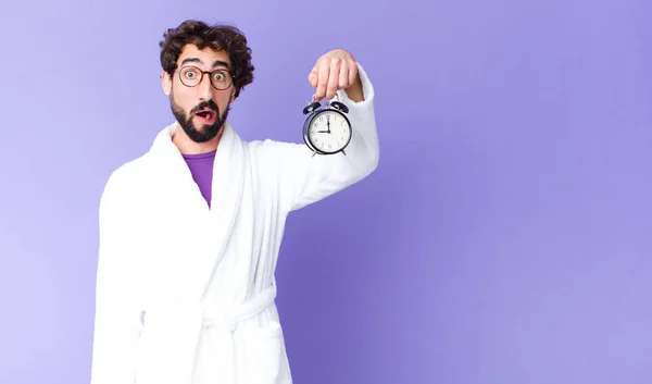Young Crazy Bearded Man Wearing Bathrobe Holding Alarm Clock — Stock Photo, Image