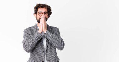 Genç çılgın iş adamı mutlu, neşeli, şanslı ve şaşırmış görünüyor. İki eli de düz duvara dayalı.