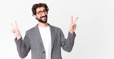 Genç çılgın işadamı gülümsüyor ve mutlu görünüyor, arkadaş canlısı ve memnun, iki elini de duvara dayayıp zafer ya da barış işareti yapıyor.