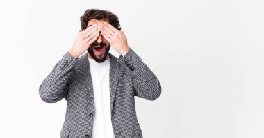 Genç çılgın iş adamı gülümsüyor ve mutlu hissediyor, iki eliyle gözlerini kapatıyor ve düz duvara karşı inanılmaz bir sürpriz bekliyor.