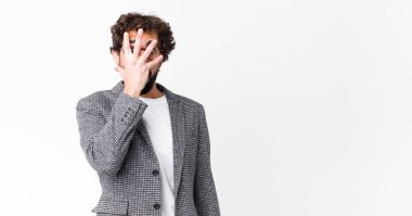 Genç çılgın iş adamı şok olmuş, korkmuş ya da korkmuş görünüyor. Yüzü elle kaplanmış ve parmaklarının arasından düz duvara bakıyor.