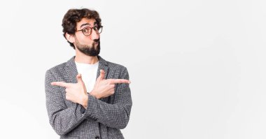 Kafası karışmış, güvensiz ve düz duvara karşı şüpheyle zıt yönlere bakan genç çılgın iş adamı.