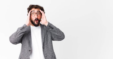 Genç çılgın iş adamı heyecanlı ve şaşırmış görünüyor, ağzı açık, elleri başının üstünde, düz duvara karşı şanslı bir kazanan gibi hissediyor.