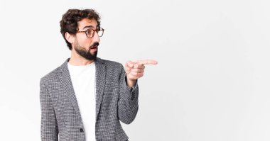 Genç çılgın iş adamı şok olmuş ve şaşırmış hissediyor, şaşırmış ve şaşkınlıkla yukarı bakıyor, şaşırmış, ağzı açık bir şekilde düz duvara bakıyor