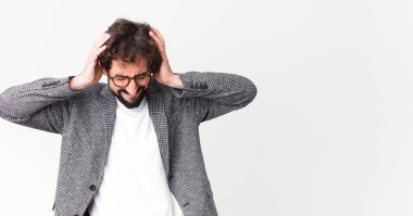 Genç çılgın iş adamı stresli ve hayal kırıklığına uğramış hissediyor. Yumruk yumruğa, yorgun, mutsuz ve migreni düz duvara dayanmış hissediyor.