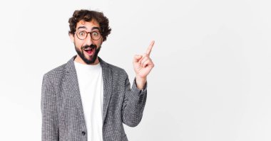 Genç çılgın iş adamı bir fikri fark ettikten sonra mutlu ve heyecanlı bir dahi gibi hissediyor, neşeli bir şekilde parmağını kaldırıyor, eureka! yassı duvara karşı