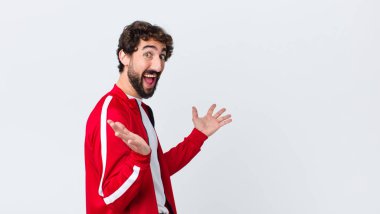 Genç sakallı adam, mutlu, heyecanlı, şaşırmış ya da şok olmuş hissediyor. Fotokopi duvarına karşı inanılmaz bir şeye gülümsüyor ve hayrete düşüyor.