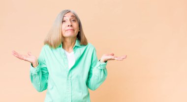 Orta yaşlı havalı bir kadın şaşkın ve kafası karışık, şüpheci, farklı seçenekleri tartıyor veya komik bir ifadeyle seçiyor.