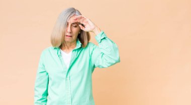 Orta yaşlı havalı bir kadın stresli, yorgun ve hayal kırıklığına uğramış görünüyor alnından ter damlıyor, umutsuz ve bitkin hissediyor.