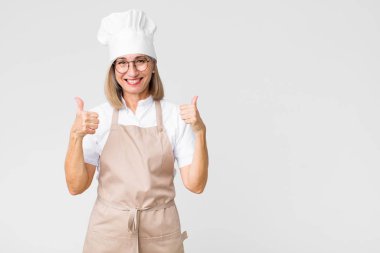 Orta yaşlı fırıncı kadın mutlu, pozitif, kendine güvenen ve başarılı bir şekilde gülümsüyor.