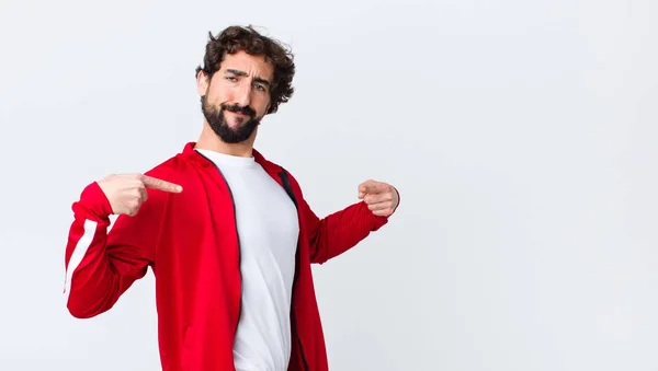 young bearded man back view looking proud, positive and casual pointing to chest with both hands against copy space wall