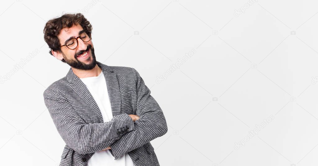young crazy businessman laughing happily with arms crossed, with a relaxed, positive and satisfied pose against flat wall