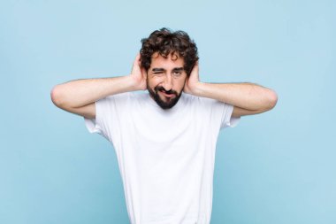 Genç çılgın sakallı adam hayal kırıklığına uğramış ve sıkılmış hissediyor, başarısızlıktan bıkmış ve bıkmış, sıkıcı sıkıcı görevlerden bıkmış, düz duvara karşı