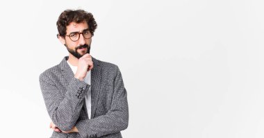 Genç çılgın iş adamı ciddi görünüyor, kafası karışık, kararsız ve düşünceli, seçenekler arasında şüpheci veya düz duvara karşı seçenekler