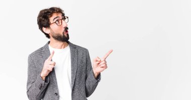 Genç çılgın iş adamı, ağzı açık, dehşete düşmüş ve şaşırmış bir şekilde duvara doğru bakıyor.