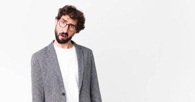 young crazy businessman feeling puzzled and confused, with a dumb, stunned expression looking at something unexpected against flat wall
