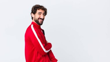 Genç sakallı adam utangaç ve neşeli bir şekilde gülüyor. Kopya uzay duvarına karşı dostane, olumlu ama güvensiz bir tavırla.