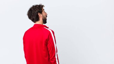 Genç sakallı adam endişeli, kafası karışık, budala bir ifadeyle, kopya alanı arıyor, kopya uzay duvarına karşı şüpheyle bakıyor.