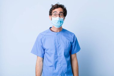 Şapşal, çılgın, şaşırmış bir ifadesi olan, yanakları şişen, doldurulmuş, şişman ve yemek dolu genç bir adam. Coronavirus konsepti