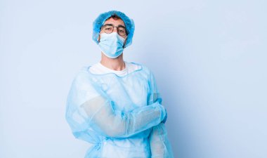 Genç adam utangaç ve neşeli bir şekilde gülüyor, arkadaş canlısı ve olumlu ama güvensiz bir tavırla. Coronavirus konsepti