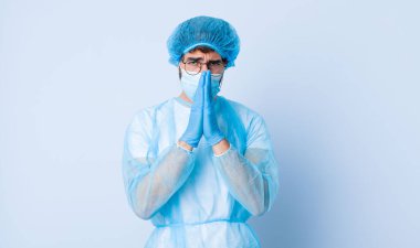 Genç adam endişeli, umutlu ve dindar, avuçlarına bastırılmış, af dileyen sadık bir şekilde dua ediyor. Coronavirus konsepti